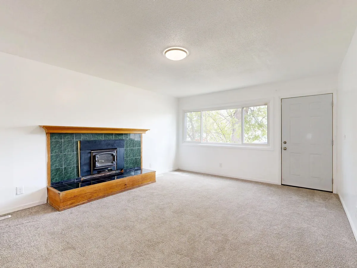 Real estate agent reviewing AI virtual staging results on a laptop next to a wide-angle photo of an empty room