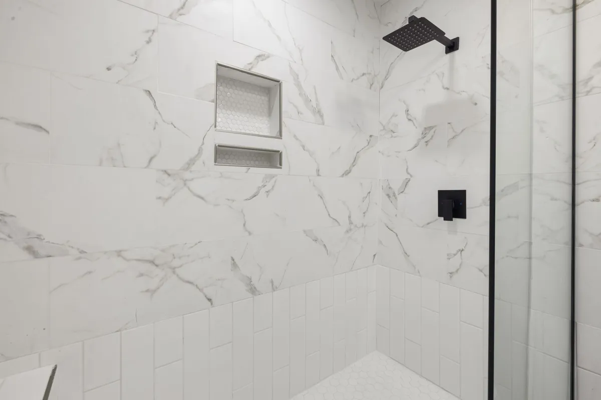 Spa-inspired bathroom with large format stone tiles, freestanding tub and warm brass fixtures