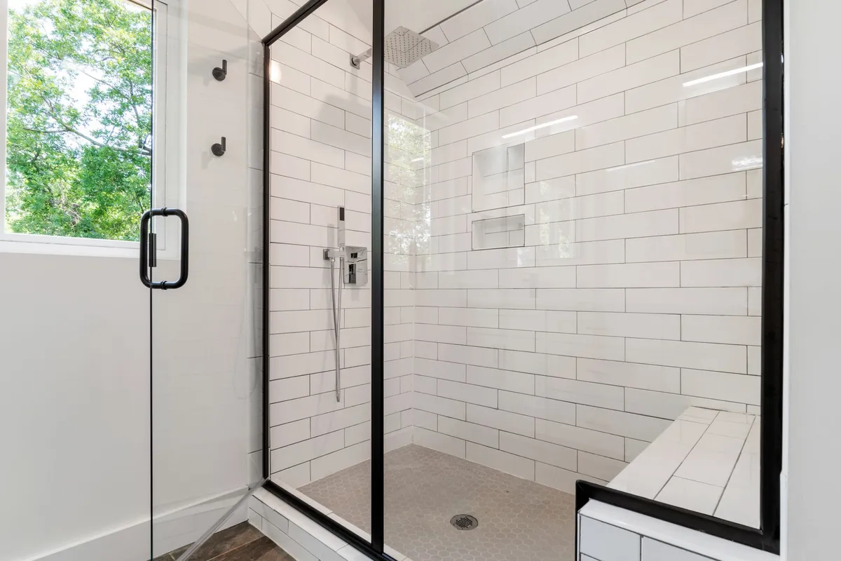 Modern bathroom with dark dramatic tile and warm brass fixtures